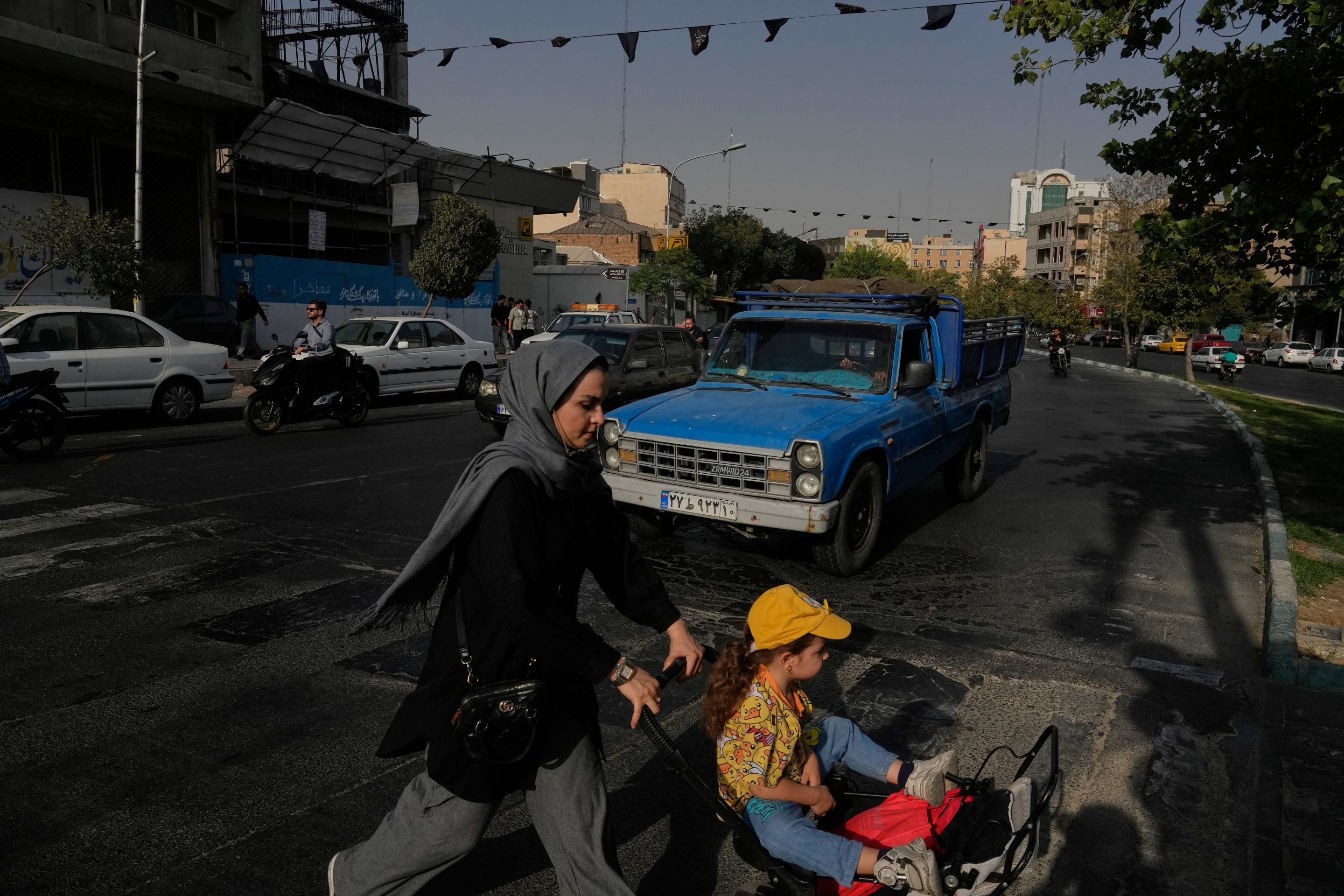 A woman crosses a street with a girl in downtown Tehran, Iran, Wednesday, July 22, 2026.