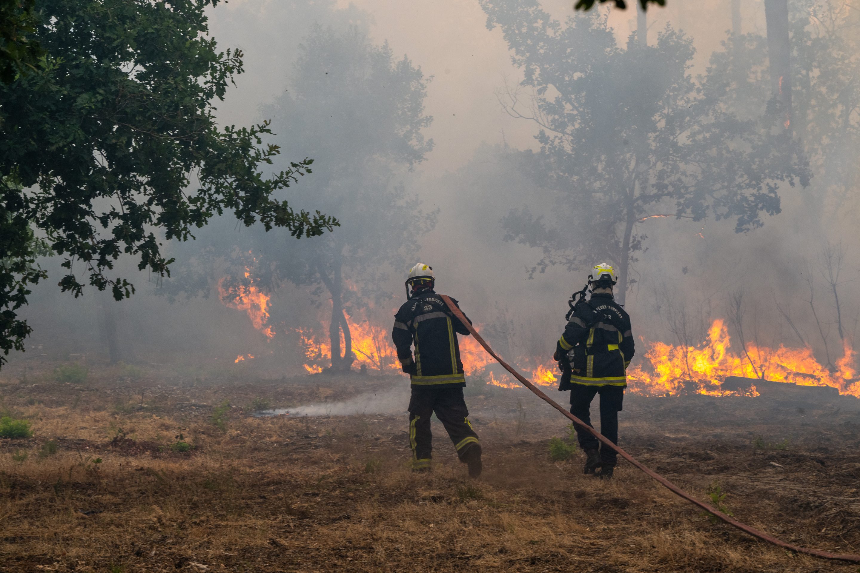 Fiirefighters spray water in a burning forest in the Lège-Cap-Ferret region, western France, Friday, July 24, 2026.