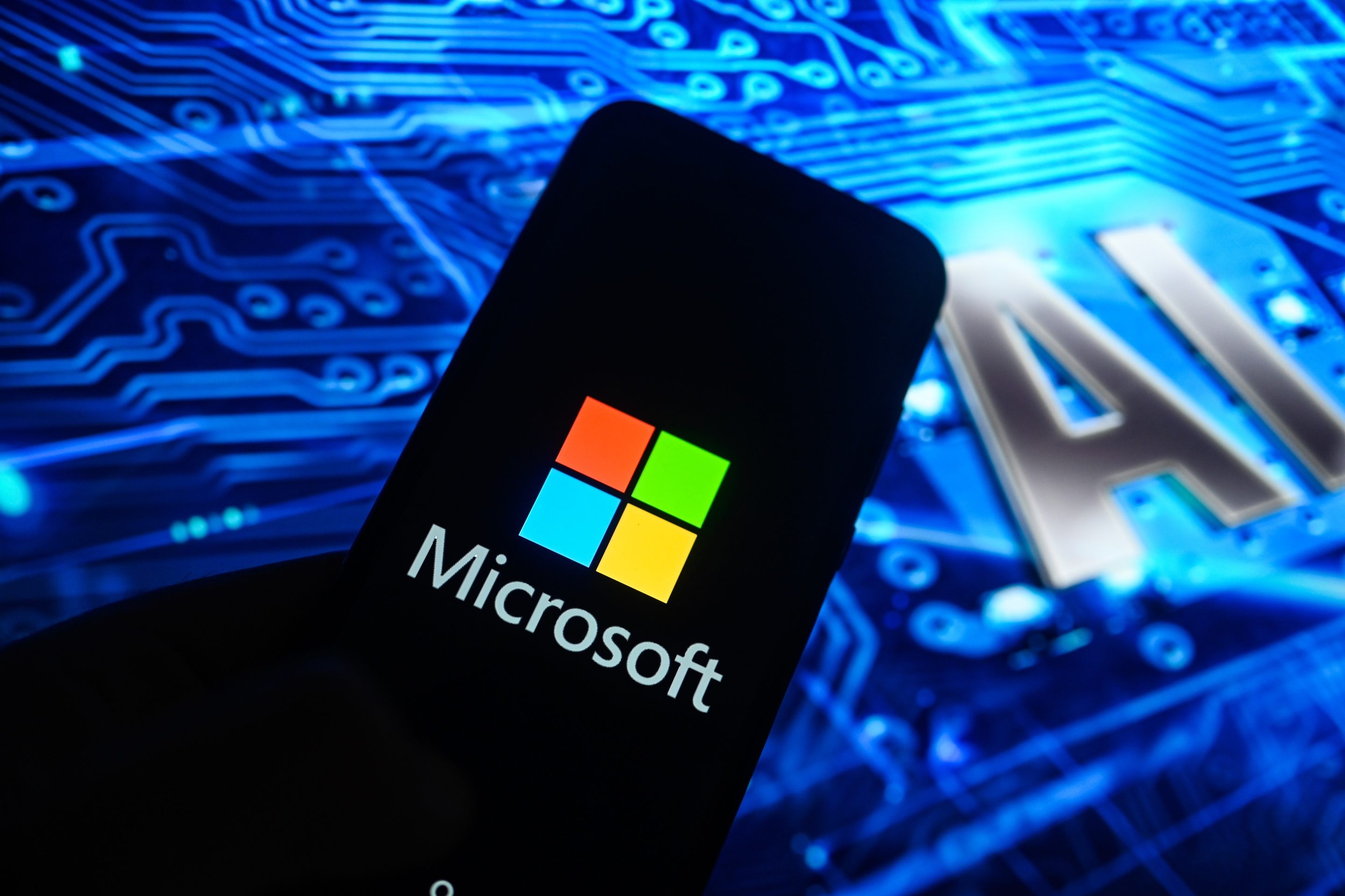 In this photo illustration, a Microsoft logo is displayed on a smartphone with Artificial Intelligence (AI) symbols on the background.