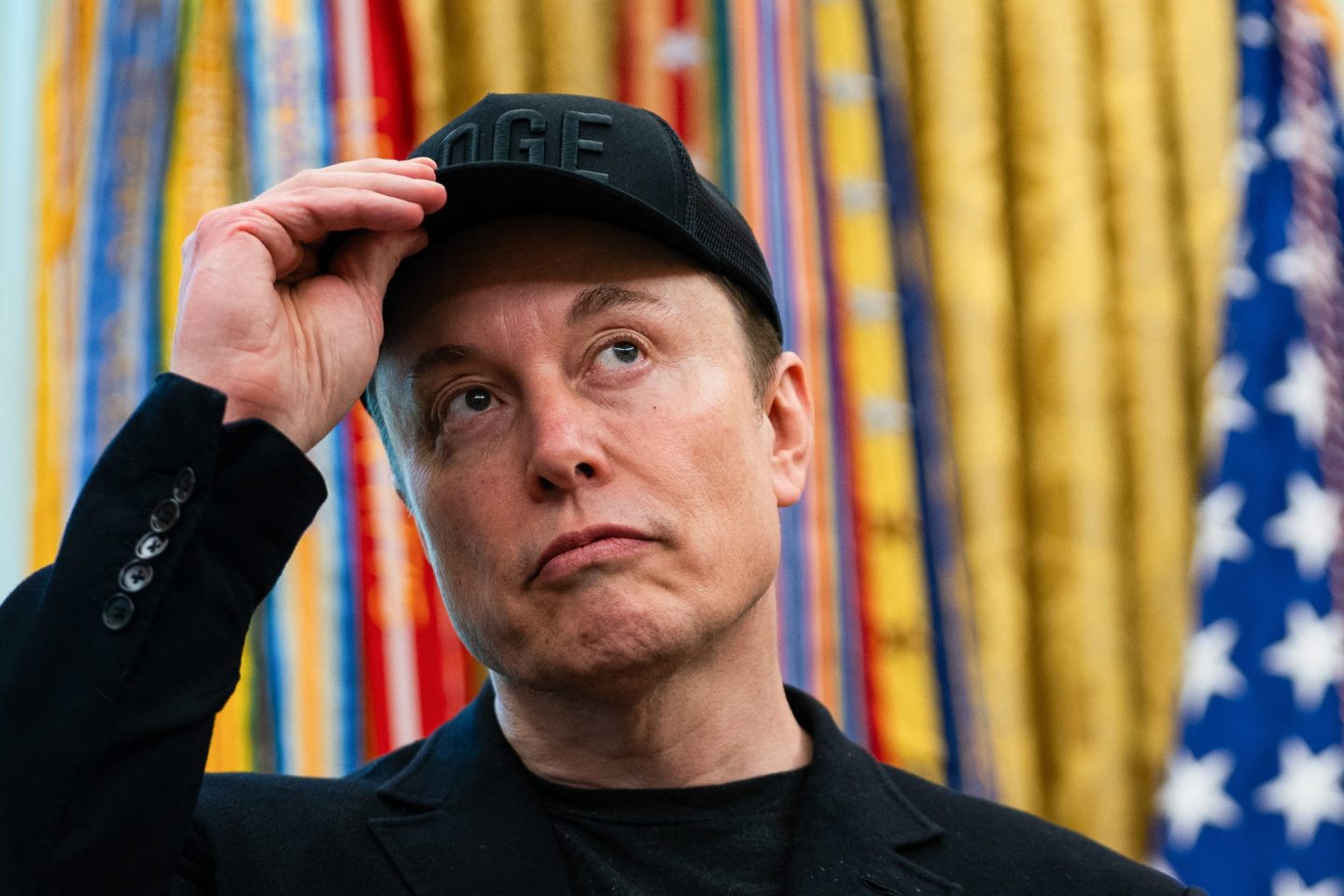 Elon Musk with a black DOGE hat