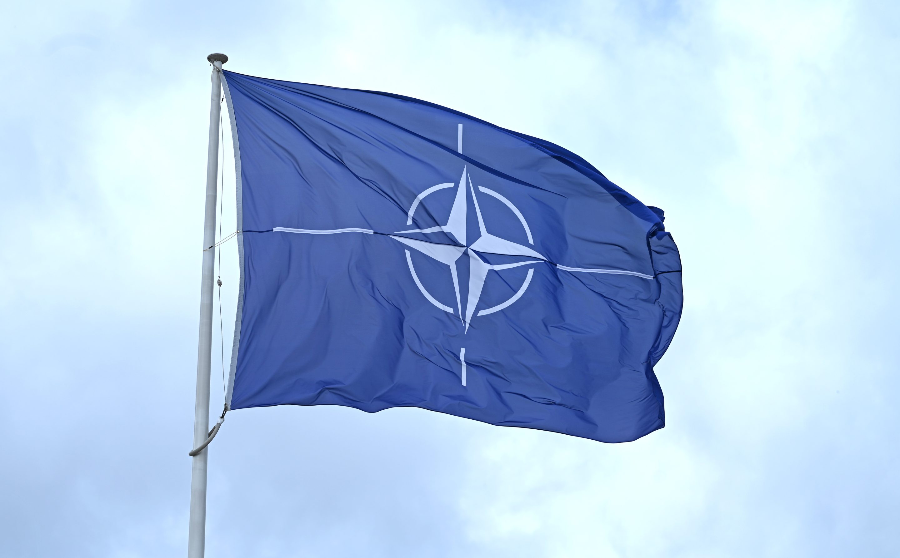 A flag with the NATO logo flies in the wind in front of the NATO headquarters in Brussels.