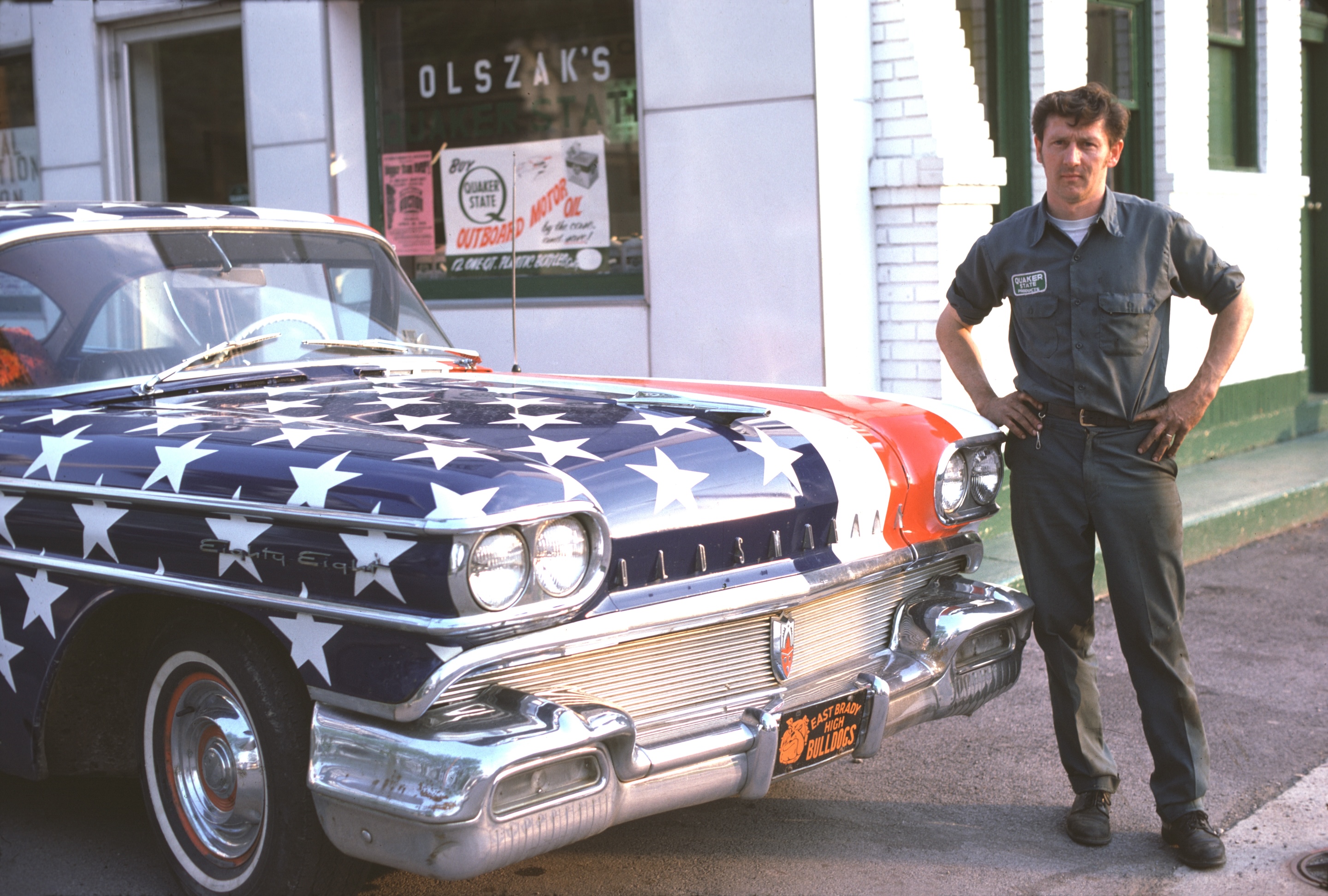 A man stands next to his Oldsmobile 88, patriotically painted with stars and stripes decorations, in celebration of the United States' bicentennial anniversary, Pennsylvania, 1976.