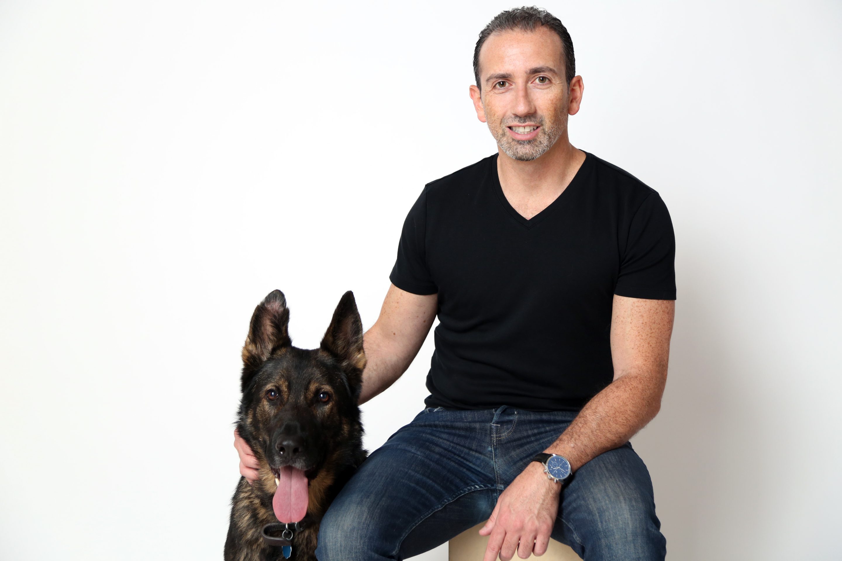 Jonathan Bensamoun (right) sits on a stool next to his German Shepherd